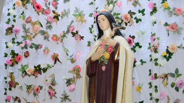 Imagem de Santa Terezinha decorada com rosas na paróquia durante a festa de Santa Terezinha em Patrocínio
