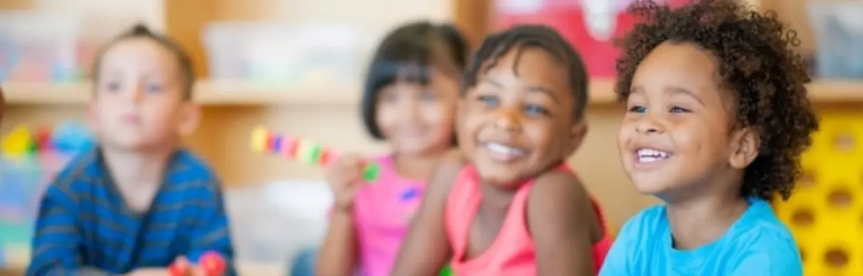 Crianças sorriem em sala de aula com brinquedos de montar, imagem da campanha do Simave em Patrocínio
