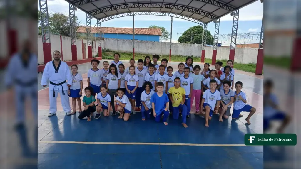 Professor Osmair Alves, de dobok e faixa preta, posa com alunos na quadra coberta da escola onde começou o taekwondo no Amir Amaral. Foto: Reprodução