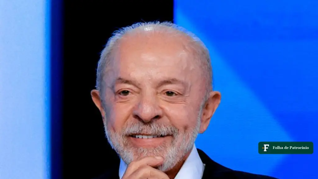 Lula sorri com a mão no queixo no estúdio do debate, na última eleição de Lula