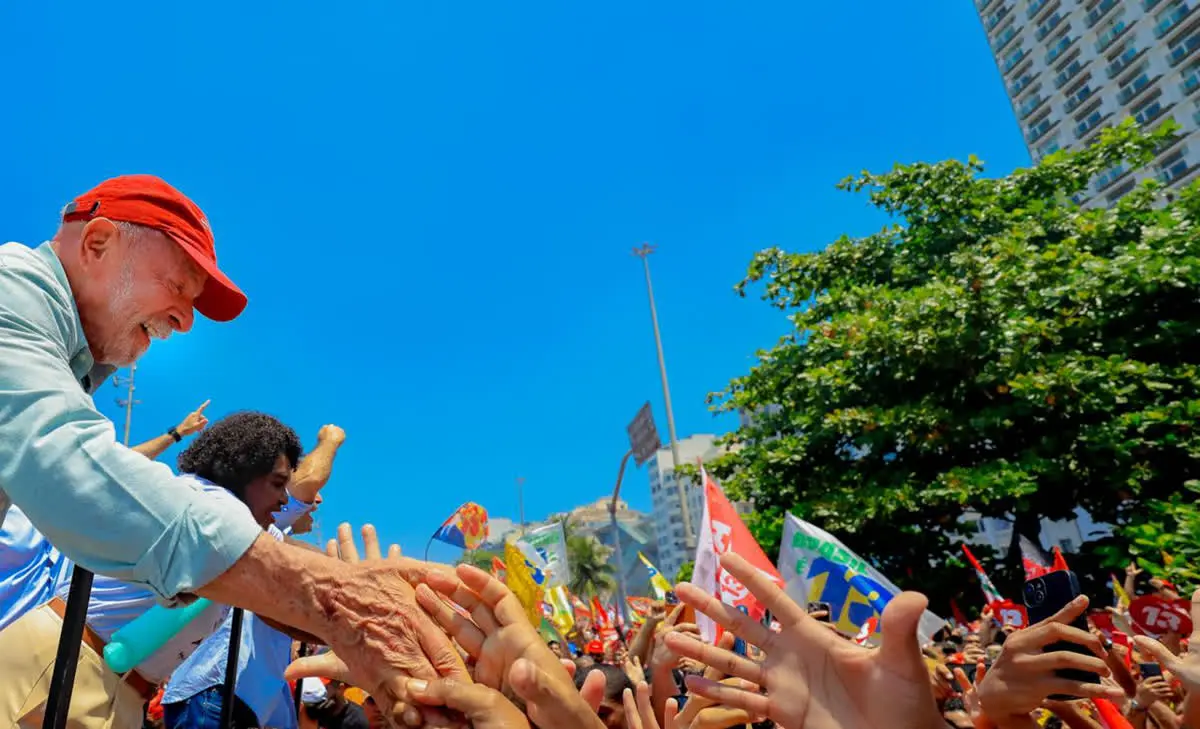 Lula de boné vermelho cumprimenta apoiadores no Rio, na reta final da última eleição de Lula