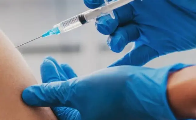Seringa da vacina contra bronquiolite nas mãos de profissional de saúde com luvas azuis