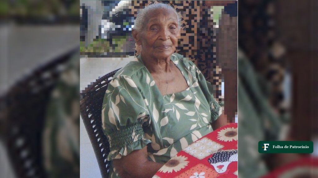 Venerina Rosa Vieira dos Santos, aos 99 anos, sentada à mesa com vestido verde estampado